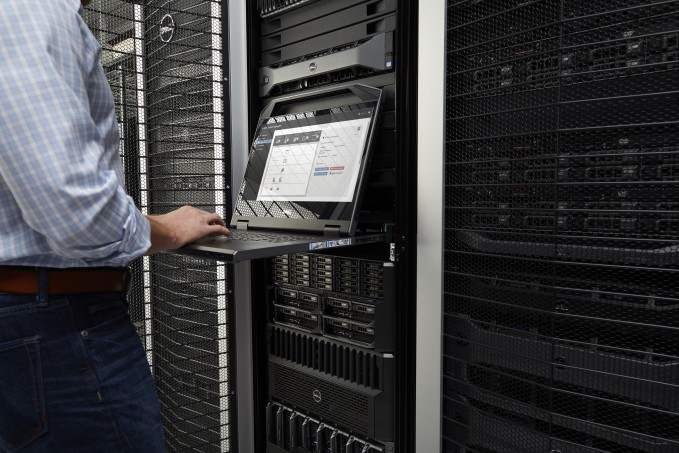 Close-up image of a man in casual clothing standing in a Dell data center with Dell rack servers, typing on a Dell rack console.